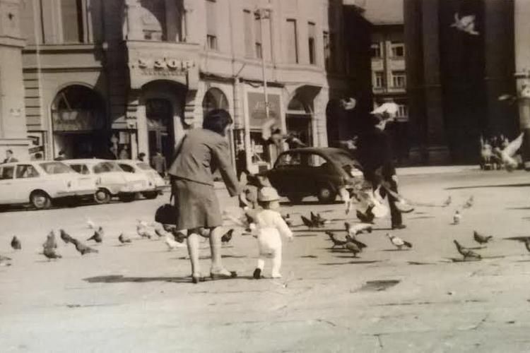 A Woman and Child Feeding Pigeons on Liberty Square, Small Cars at the Kerb, Novi Sad, 1960s